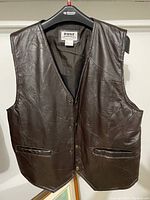 Front view of the brown leather vest showing front snap buttons, V-neck, and front pockets