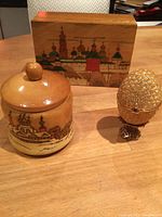 Wooden keepsake boxes and Faberge-style egg trinket box displayed on table, showing detailed hand-painted Russian church scenes.