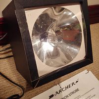 Front view of the strobe light showing reflective dish, bulb and part of the original box.