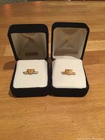 Pair of TTC service pins in black velvet presentation boxes, on wooden surface.