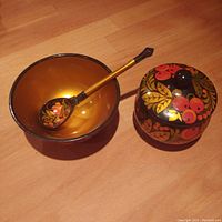 Photo of the wooden bowl, jar with lid, and spoon arranged on a wooden surface showing the hand-painted berries motif.