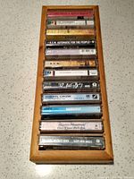 Top view of all twelve cassette tapes arranged vertically inside a wooden container.