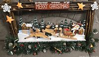 Front view of wooden Christmas wall hanging featuring Santa in sleigh, two reindeer, pine trees, stars, snowflakes, and Merry Christmas sign