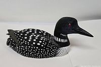 Front view of the hand-painted collectible loon figurine showing spotted black and white plumage and red eyes.