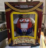 Front box view of the official limited edition holiday collectible M&M Nutcracker candy dispenser in packaging.