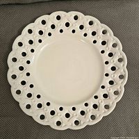 Top view of the white decorative plate showing intricate pierced floral pattern around edge.