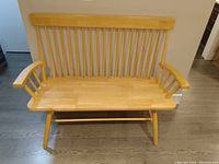 Photo of an extra wide wooden chair showing its slatted backrest, armrests, and broad seat.