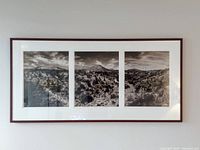 Framed triptych of three black and white landscape photographs in a wood frame with white matting, showing mountainous desert scenery.
