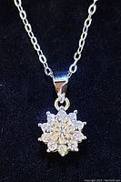 Close-up of moissanite pendant with central round stone and surrounding smaller stones set in sterling silver on chain.