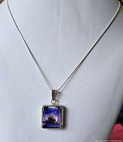 Front view of necklace showing delicate silver chain and rectangular blue pendant with ship motif.