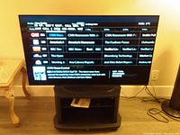 Front view of Sony Bravia TV powered on displaying channel menu with included stand