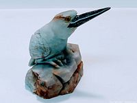 Front angle showing detailed carving and color variations of bird figurine on stone base.