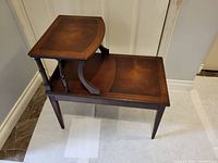 Front angle showing the full two-tier design with leather inlays and tapered legs.