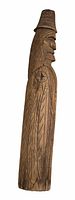 Photo of a hand-carved wooden figurine, side profile showing detailed hat, facial features, and patterned cloak