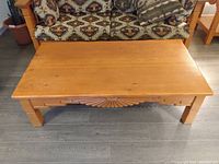 Top and front view of the rectangular wood coffee table showing carved details and surface wear.