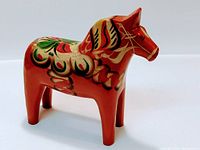 Image of a painted wooden horse figurine showing front and side view with floral decorative painting and blocky shape