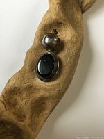 Photo of front view of American Indian sterling silver pendant with black onyx stone on natural wood background