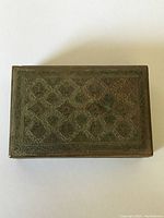 Top view showing intricate brass engravings and patina on the antique trinket box.