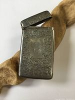 Front side of hand-etched sterling silver card case showing ornate scrollwork and monogram.