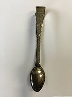 Full length image of the sterling silver sugar tongs showing overall shape and detail.