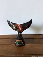 Front view of the wooden whale tail showing detailed hand painted traditional NWC design and colors