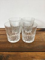 Front view of the set of four clear crystal glasses with vertical and diamond cut patterns.