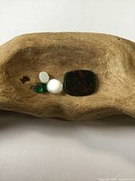 Gemstone group displayed on carved wooden bowl: bloodstone, opal, moonstone, two emeralds.