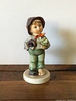 Front view of 'Lost Stocking' Hummel figurine, showing detailed facial features, clothing, and items held.