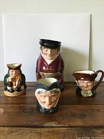 Front view of four Royal Doulton Toby Jugs showing detailed faces and period costume.