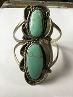 Close-up front view showing the large faux turquoise stones and intricate silver-tone metalwork with leaf and rope designs.