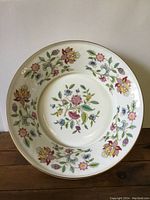 Top-down view of the Minton porcelain bowl showing the full floral pattern and gold rim, placed on a wood surface.