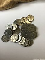 Various U.S. Jefferson nickels grouped together on a white surface, showing coin faces with different wear and patinas.