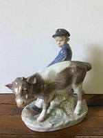 Side view of porcelain figurine depicting boy and calf, showing detailed painting and glossy finish.