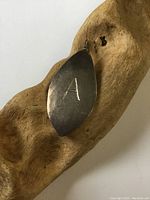 Front view of sterling silver leaf-shaped pendant with engraved letter 'A' on surface, showing tarnish and surface wear.