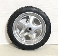 Photo of one 15-inch flat free tire with shiny silver metal rim against white background.