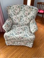 Front view of the floral upholstered armchair showing padded arms, tufted backrest, and skirted base.
