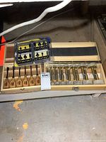 Wooden case opened displaying Forster bits with brass heads and wooden handles alongside wood carving tools.