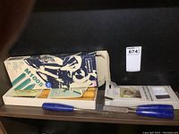 Photo of original packaging and chisels with blue handles placed beside box