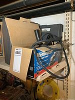 Angle grinder box with power cord and handle visible on shelf