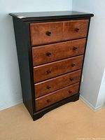 Front view of the 5-drawer modern high boy dresser showing black frame and wood-finished drawer fronts with knobs.
