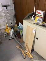 Overview photo of vacuum sander, broom, sweeping compound and storage cabinet in a basement.