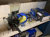 Vintage timing tester, plumbing snake, brush and flap wheel kit, scraper and battery load tester arranged on shelves