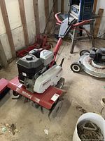Side view of red and white White Outdoor rototiller in workshop