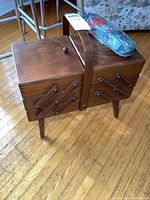 Front diagonal view of the closed wooden sewing box with plastic sewing kit on top.