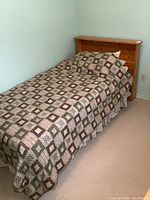 Front view of single bed with patchwork quilt bedding and solid wood headboard.