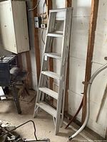 Full view of the 6 ft aluminum step ladder leaning against a wall, showing its five steps and general condition.