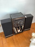 Front view of full stereo system cabinet flanked by two speakers on hardwood floor