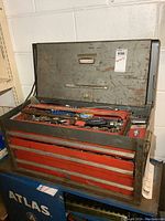 Front view of open Craftsman metal toolbox showing drawers and top lid open with tools inside