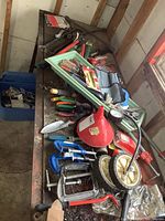 Metal workbench with an assortment of hand tools including clamps, screwdrivers, pry bars, a funnel, and wheels.