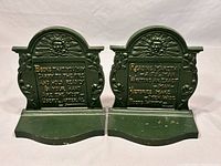 Pair of green painted cast iron bookends with gold text, front view.